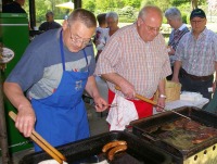 Das Foto zeigt zwei Männer an einem Grill